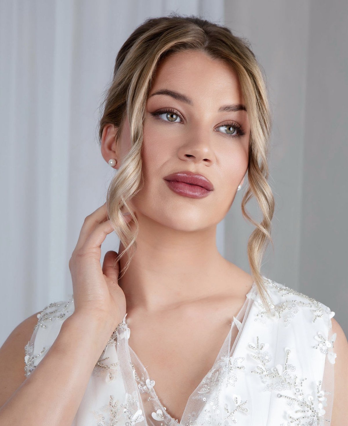 Bridal makeup look: client with a soft pinned-up style, ringlets and a berry lip, wearing a lace-detail bridal top