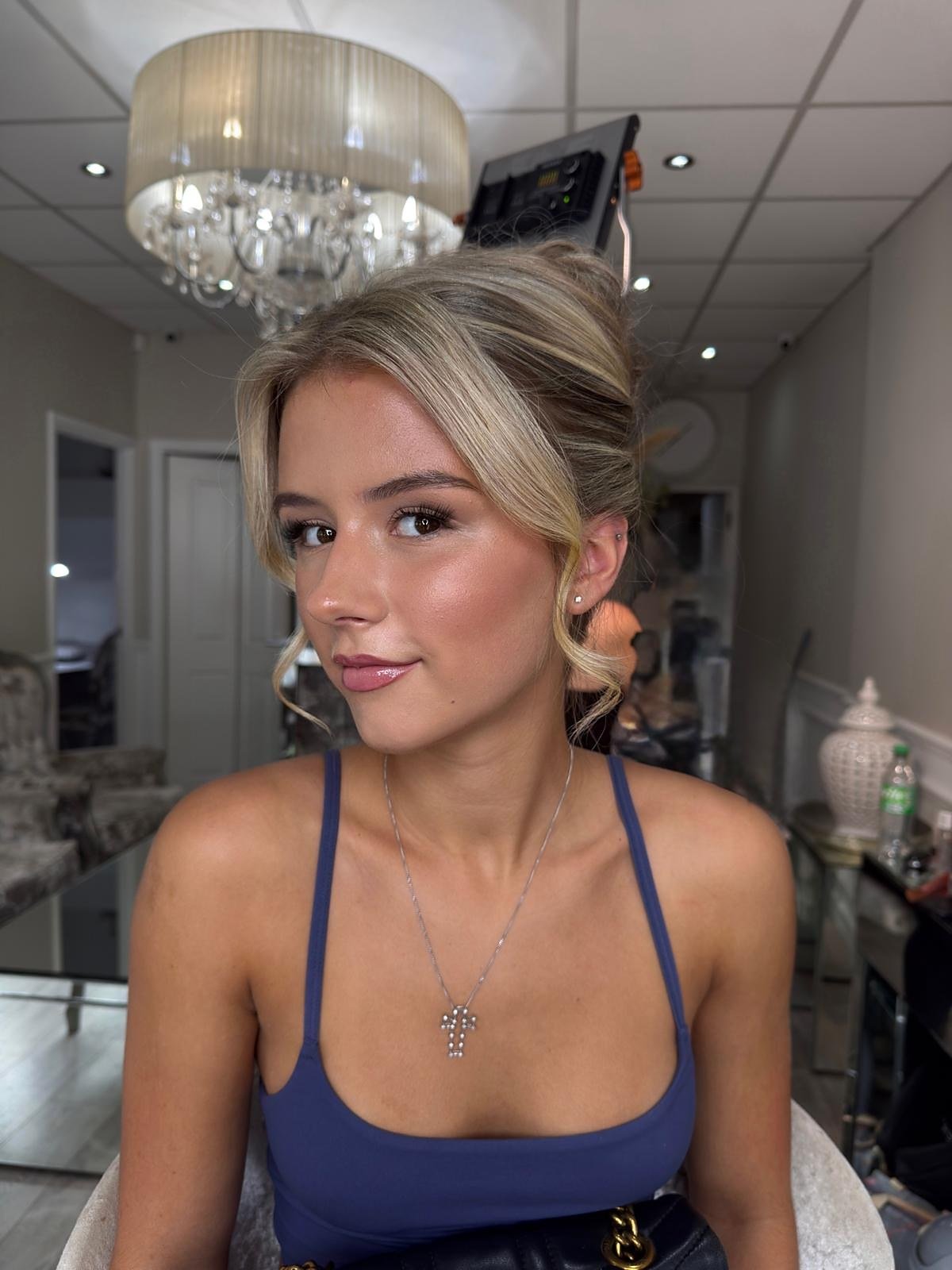 Occasion makeup look: client with a soft pinned-up blonde style, fresh glowing skin and a rose gloss lip, in a navy top